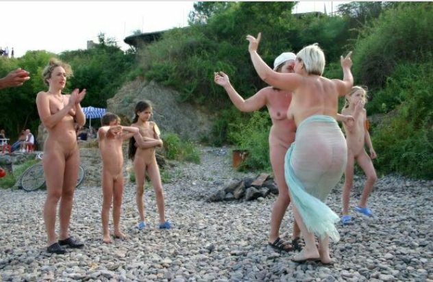The company of nudists dances on a beach The company of nudists dances on a beach