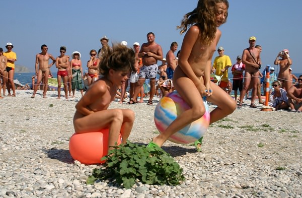 Family nudism - competition of young girls of nudists on jumps on a ball Family nudism - competition of young girls of nudists on jumps on a ball